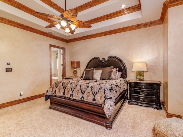 carpeted bedroom with ceiling fan, a raised ceiling, ornamental molding, and ensuite bathroom