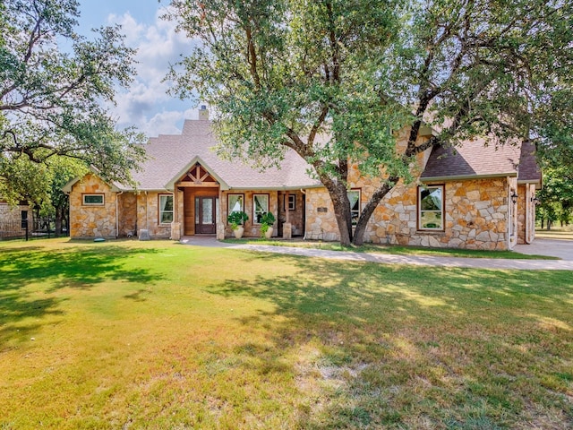 view of front facade with a front yard, stone siding, and a chimney