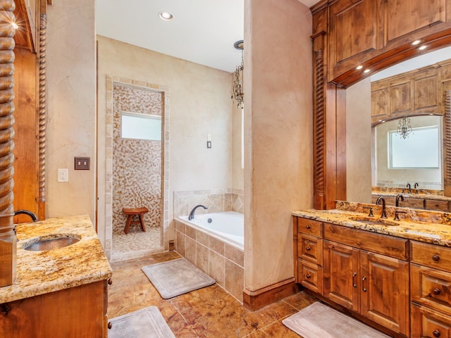 bathroom with a relaxing tiled tub, tile patterned flooring, and vanity