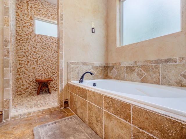 bathroom with tiled tub and tile patterned flooring