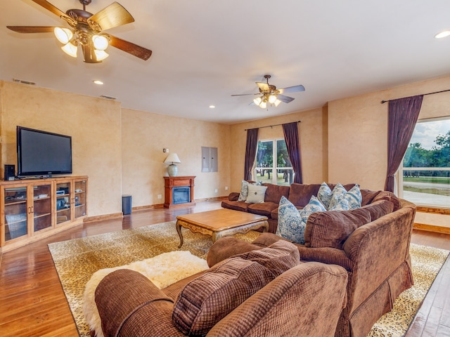 living room with ceiling fan, electric panel, and wood-type flooring