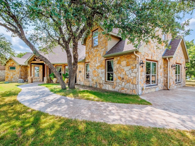 view of front of property with a shingled roof and a front yard