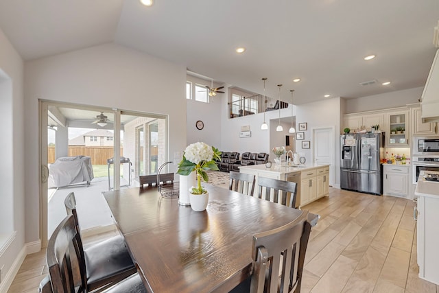 dining area with a healthy amount of sunlight, high vaulted ceiling, sink, and ceiling fan