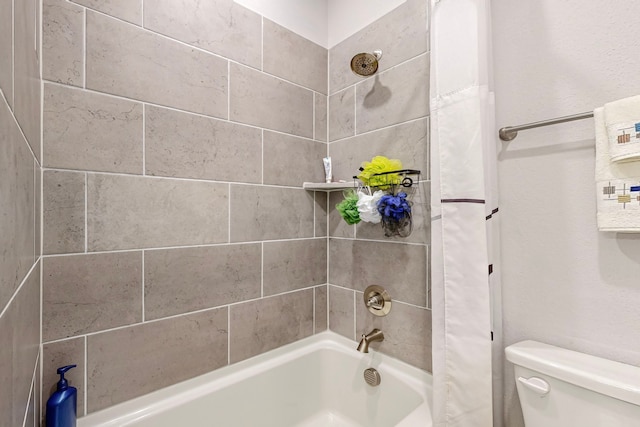 bathroom featuring toilet and tiled shower / bath