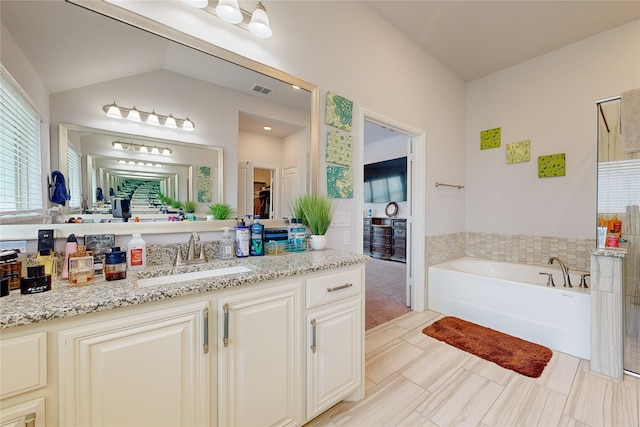 bathroom featuring tile patterned floors, vanity, a washtub, and lofted ceiling