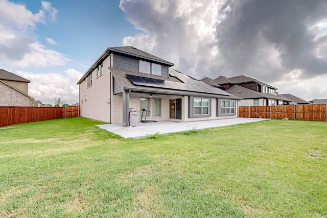 rear view of property with a patio, a yard, and solar panels