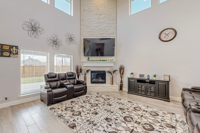 living room featuring light hardwood / wood-style flooring, a fireplace, and a high ceiling