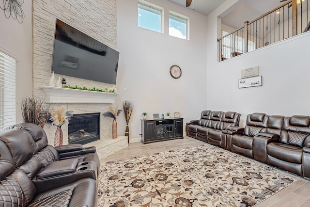 living room with wood-type flooring, a stone fireplace, and a towering ceiling