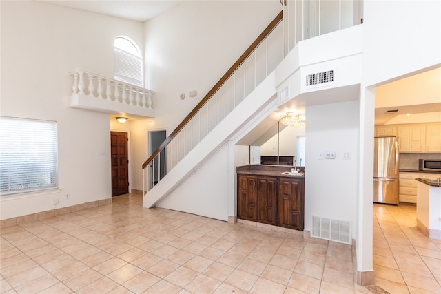 interior space featuring plenty of natural light, sink, light tile patterned floors, and a towering ceiling