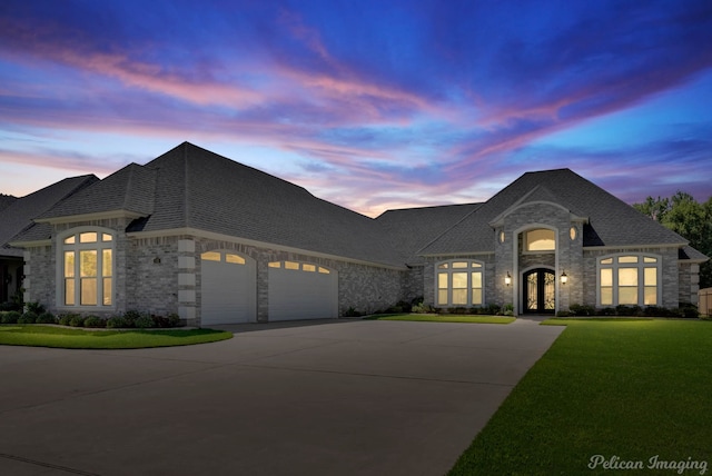 french provincial home with a garage and a yard