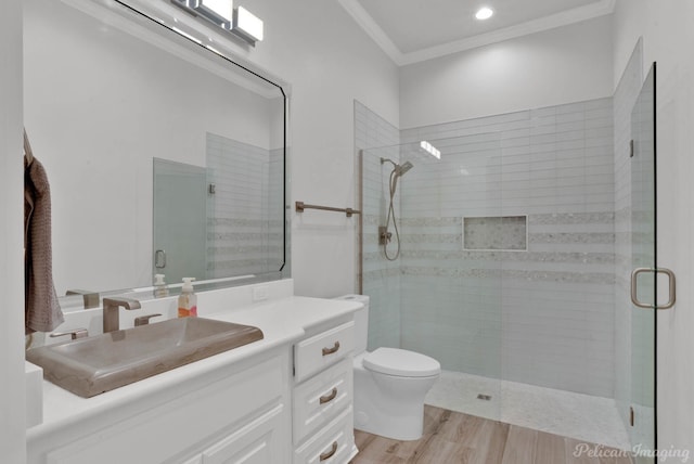 bathroom with an enclosed shower, vanity, toilet, ornamental molding, and hardwood / wood-style flooring