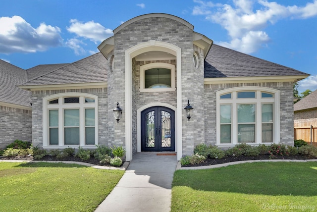 view of exterior entry featuring french doors and a lawn