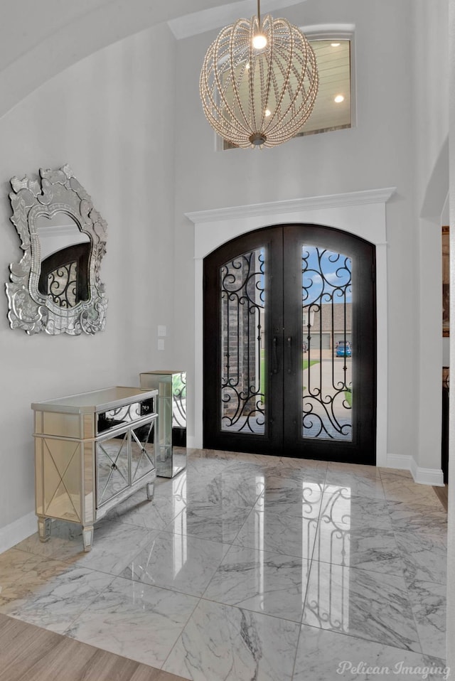 entrance foyer with a towering ceiling, french doors, and a notable chandelier