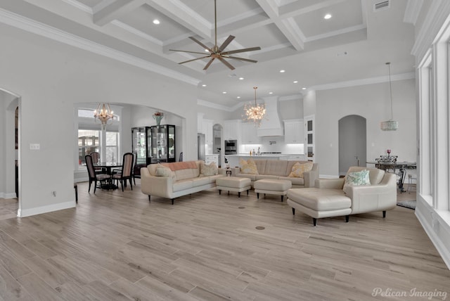 living room featuring light wood-type flooring, a towering ceiling, ceiling fan with notable chandelier, and coffered ceiling