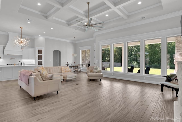 living room featuring ceiling fan with notable chandelier, a high ceiling, light hardwood / wood-style flooring, and coffered ceiling