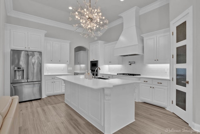 kitchen featuring backsplash, an island with sink, premium range hood, and stainless steel appliances