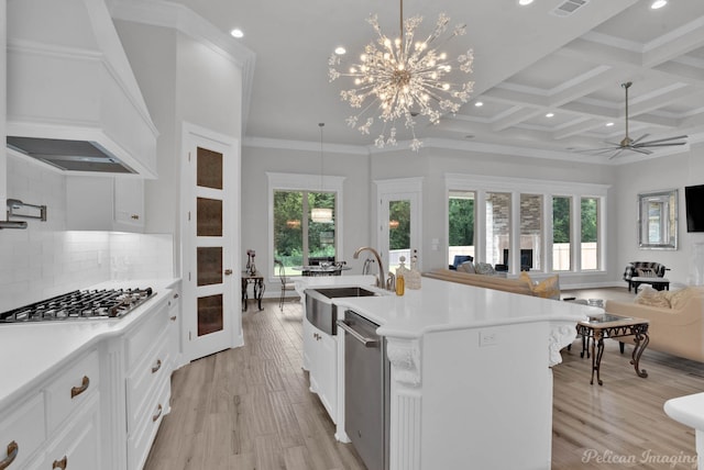 kitchen with custom exhaust hood, stainless steel appliances, an island with sink, hanging light fixtures, and coffered ceiling