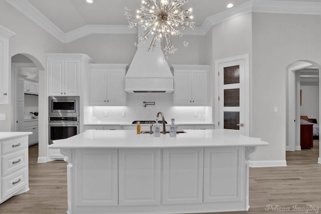 kitchen with tasteful backsplash, pendant lighting, a center island with sink, white cabinetry, and stainless steel appliances