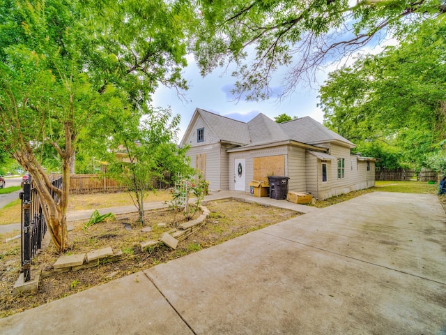 view of side of home featuring driveway, a patio, and fence