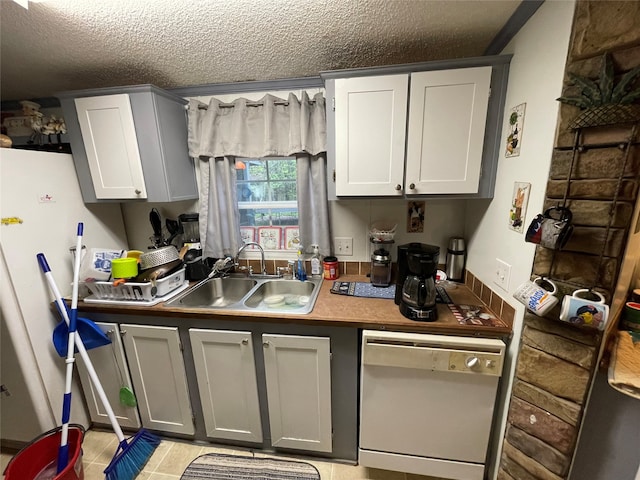 kitchen with light tile patterned flooring, a textured ceiling, dishwasher, gray cabinets, and sink