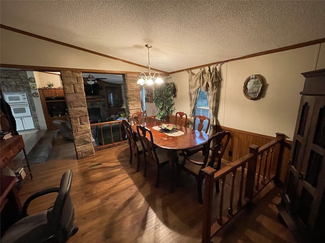 dining area featuring vaulted ceiling, a fireplace, a textured ceiling, ceiling fan with notable chandelier, and dark hardwood / wood-style flooring