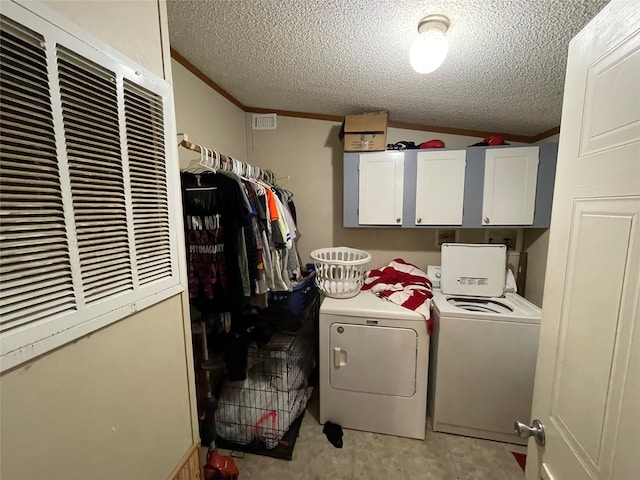 laundry room featuring washer and clothes dryer, cabinets, and a textured ceiling