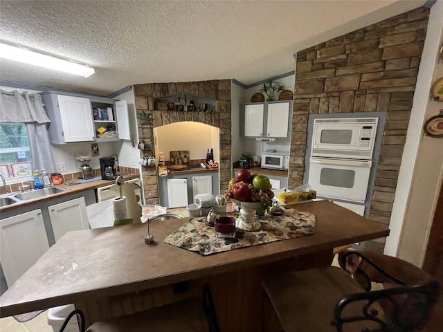 kitchen featuring sink, a textured ceiling, white cabinets, and white appliances