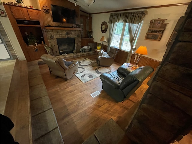 living room with a fireplace, ornamental molding, built in shelves, and hardwood / wood-style floors