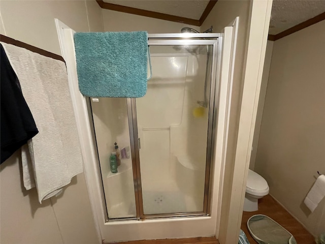 bathroom with ornamental molding, vaulted ceiling, an enclosed shower, toilet, and a textured ceiling