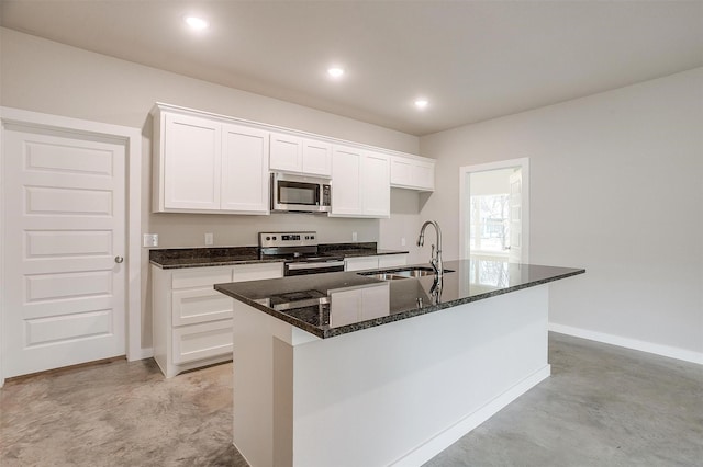 kitchen with white cabinets, appliances with stainless steel finishes, sink, and a center island with sink