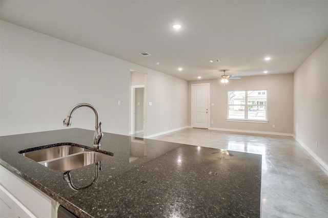 kitchen featuring ceiling fan, sink, white cabinets, and dark stone counters