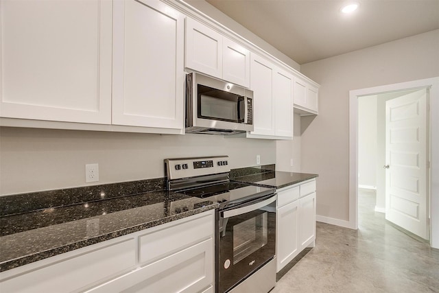 kitchen with appliances with stainless steel finishes, white cabinets, and dark stone counters