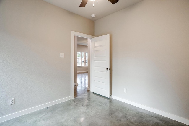 unfurnished room with ceiling fan and concrete floors