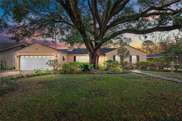 ranch-style house featuring a garage and a lawn