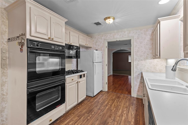 kitchen with dark wood-type flooring, sink, crown molding, black appliances, and cream cabinetry