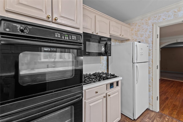 kitchen featuring dark hardwood / wood-style floors, ornamental molding, and black appliances