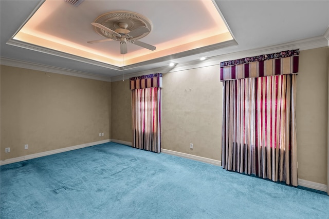 empty room featuring a tray ceiling, ceiling fan, crown molding, and carpet