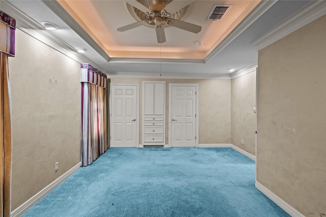 unfurnished bedroom featuring carpet flooring, ceiling fan, a raised ceiling, and ornamental molding