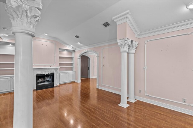 unfurnished living room with built in shelves, vaulted ceiling, ornate columns, and a premium fireplace