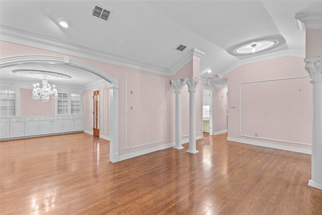 interior space featuring an inviting chandelier, lofted ceiling, crown molding, and decorative columns