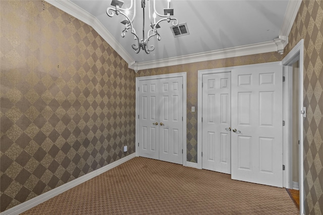 unfurnished bedroom featuring carpet, a notable chandelier, ornamental molding, and multiple closets