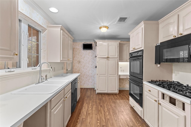 kitchen with crown molding, sink, black appliances, and hardwood / wood-style flooring