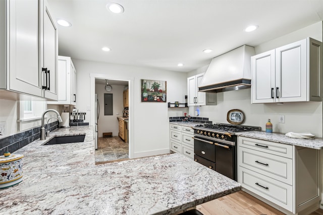 kitchen featuring premium range hood, white cabinets, sink, double oven range, and light hardwood / wood-style flooring