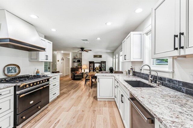 kitchen featuring premium range hood, ceiling fan, light hardwood / wood-style floors, double oven range, and sink