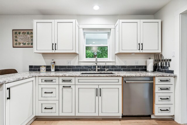 kitchen with white cabinetry, sink, dishwasher, light stone counters, and light hardwood / wood-style floors