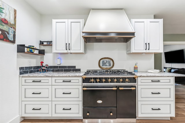 kitchen featuring white cabinetry, range with two ovens, light wood-type flooring, and custom range hood