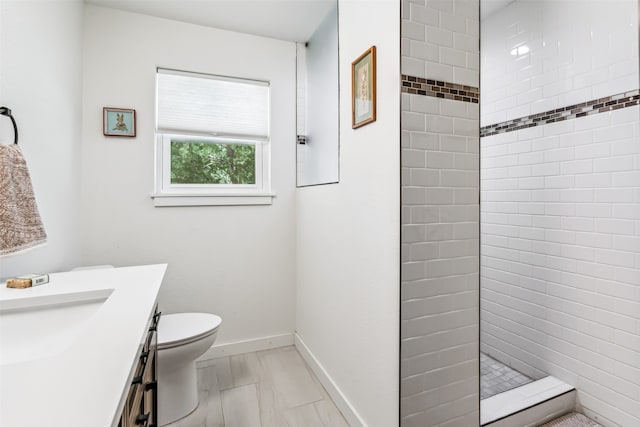 bathroom featuring tiled shower, vanity, and toilet