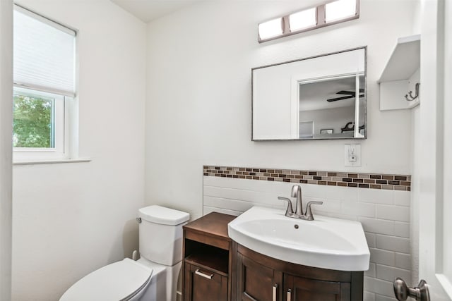 bathroom featuring vanity, tile walls, ceiling fan, and toilet