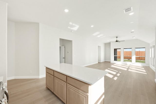 kitchen with ceiling fan, light brown cabinetry, a kitchen island, and light hardwood / wood-style floors