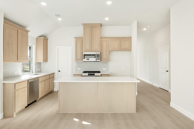 kitchen featuring appliances with stainless steel finishes, a center island, light hardwood / wood-style floors, and vaulted ceiling